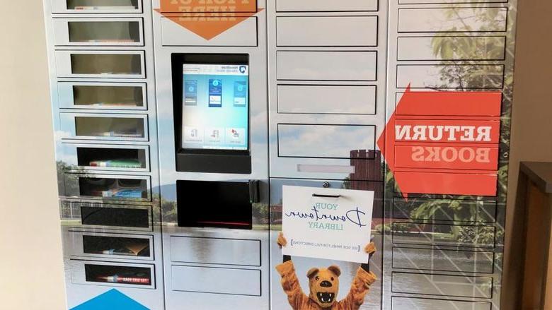 tall metal locker system with central touchscreen and dozens of small narrow doors, some with windows to see book covers