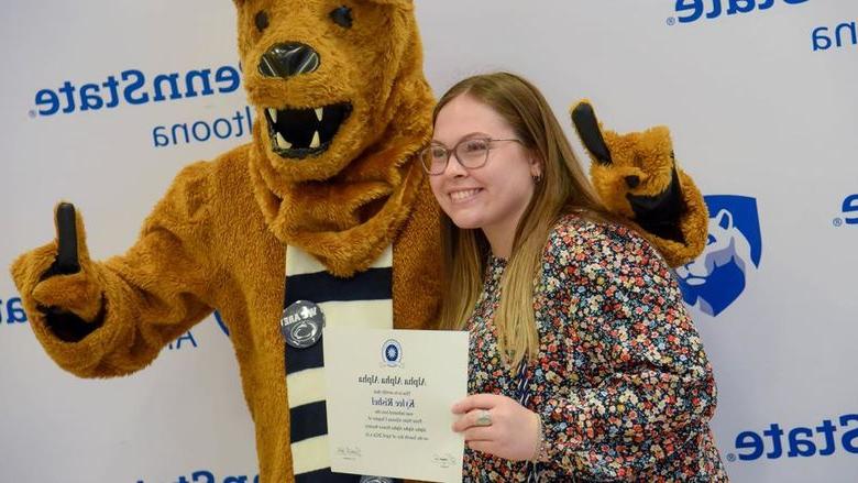 Psychology major Kylee Rishel poses with her certificate and the Nittany Lion after the induction ceremony.