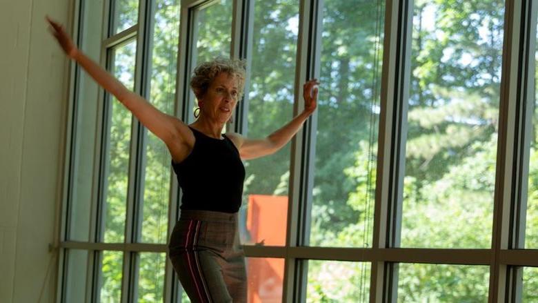 Michele Dunleavy dances in a dance studio in front of windows